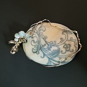 Pendant. Shell carved and wrapped in Metal with blue beads.